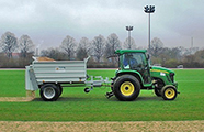 Kompakttraktor mit Sandstreuer auf einem Rasensportplatz