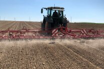 Traktor mit Striegel fährt über Ackerland
